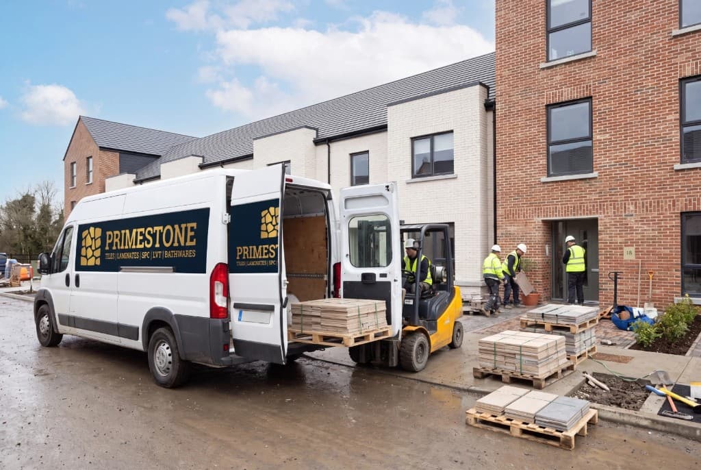 Primestone van and forklift delivering tile pallets outside modern brick townhouses
